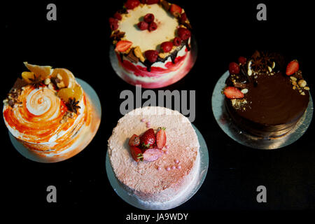 Die verschiedenen Kuchen drehen reibungslos auf der Basis. Gibt es Schokolade, Karotten, Joghurt und Beeren. Stockfoto