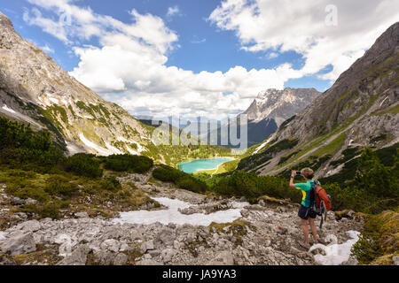 Wanderer unter Bild mit Handy des Zugspitzmassivs und See Seebensee, Ehrwald, Tirol, Österreich Stockfoto