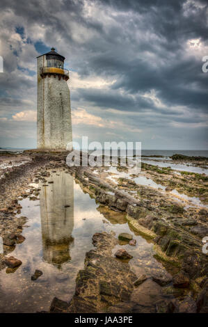 Bevorstehende Southerness Leuchtturm (reflektiert im Rockpool), Dumfries and Galloway, Schottland zu stürmen. Hoher Dynamikbereich Bild. Stockfoto