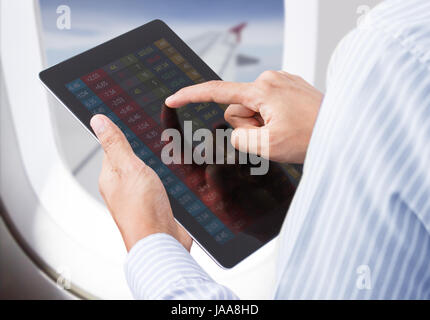 Geschäftsmann, Prüfung Aktienmarkt auf Tablet im Flugzeug Stockfoto