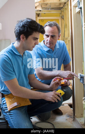 Elektriker mit Lehrling arbeitet im neuen Zuhause Stockfoto