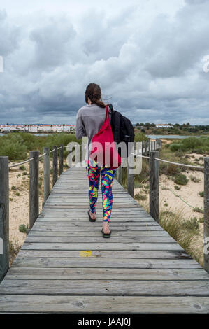 Frau touristischen Spaziergang entlang der hölzernen Boarwalk auf Praia de Cabanas, Portugal Stockfoto