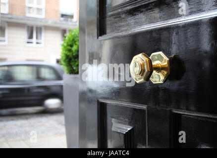 Ein typisch britischer Messing Türgriff auf eine Haustür auf einer zentralen Straße von London, UK. London Taxi übergibt. Stockfoto