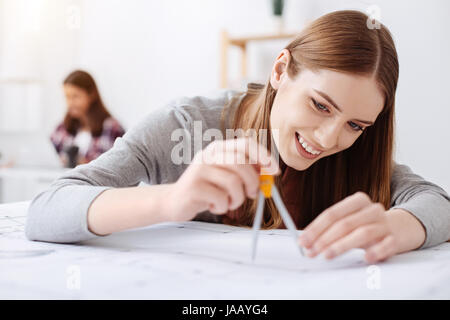 Kleine Details. Ursprüngliche sorgfältige analytische Dame, die sicherstellen, dass alle Zeichnungen werden beim Sitzen am Tisch und an einem Projekt arbeiten präzise Stockfoto