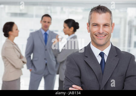 Lächelnd posiert mit Mitarbeitern im Hintergrund in hellen Büro manager Stockfoto