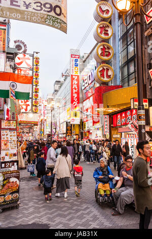 Blick entlang der berühmten Einkaufsstraße in Dotonbori, das Genuss und Entertainment Viertel von Osaka. Beleuchtete Schilder, Menschenmassen, Dämmerung. Stockfoto