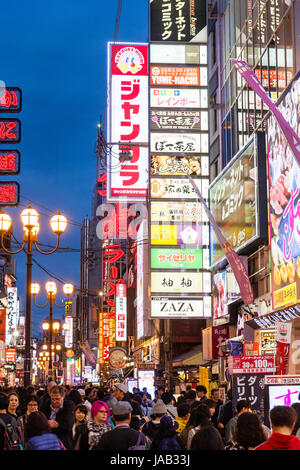 Blick entlang der Hauptstraße in Dotonbori, das Vergnügen und Unterhaltung Zentrum von Osaka in der Nacht. Beleuchtete Schilder und belebten Straße. Stockfoto