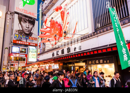 Dotonbori Viertel von Osaka in der Nacht Wahrzeichen, Krabben Schild über Eingang Kanidoraku Restaurant mit Massen Fräsen um im Vordergrund. Stockfoto