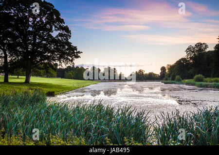 Ein Sommer Sonnenaufgang über dem See bei Lydiard Park in Swindon, Wiltshire. Stockfoto