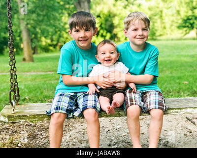 Drei Jungs auf einer Schaukel Stockfoto