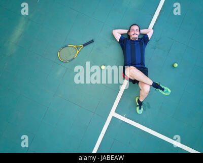 Müde Tennisspieler lag auf Platz oberhalb Ansicht. Mann verliert Tennis-Spiel Stockfoto