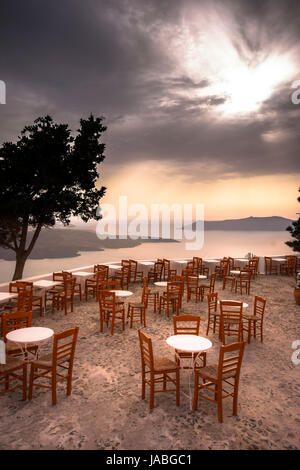 Erstaunlich Abendlicher Blick von Fira, die Caldera, den Vulkan von Santorini, Griechenland mit Kreuzfahrtschiffen bei Sonnenuntergang. bewölkt dramatische Himmel. Stockfoto