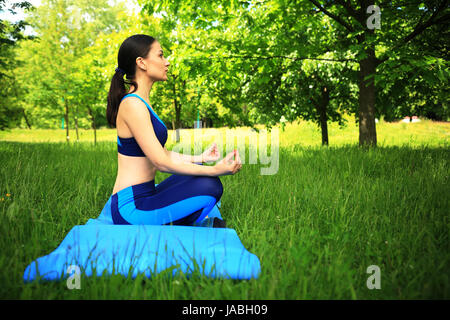 Fitness-Szene. Mädchen im Lotos Pose im Park. Hübsches Mädchen Yoga im Freien zu tun. Stockfoto