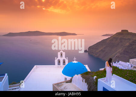 Brillante Sonnenuntergang in Fira mit einer Kirche und einem Braut auf einem Dach, Santorini, Griechenland. Stockfoto