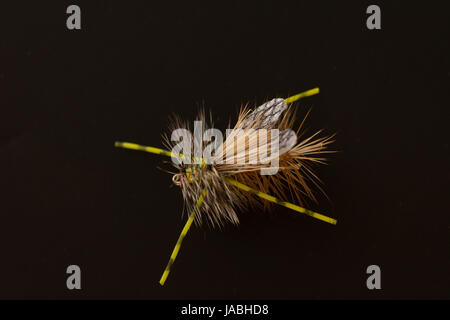 Nahaufnahme von einem olivgrünen Schaum Fliegenfischen fliegen mit weißen und schwarzen Schaumstoff Flügeln, Borsten und Antennen vor einem schwarzen Hintergrund. Stockfoto