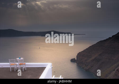 Erstaunlich Abendlicher Blick von Fira, die Caldera, den Vulkan von Santorini, Griechenland mit Kreuzfahrtschiffen bei Sonnenuntergang. bewölkt dramatische Himmel. Stockfoto