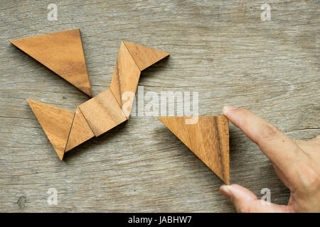 Mann halten Dreieck, Tangram-Puzzle in Vogel-Form zu erfüllen (Konzept für die Freiheit, frei leben oder entdecken Sie neue Welt) Stockfoto