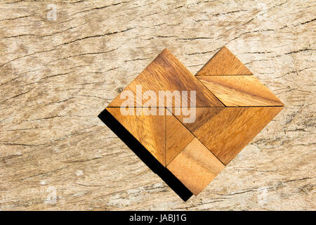 Tangram-Puzzle in Herzform auf hölzernen Hintergrund Stockfoto