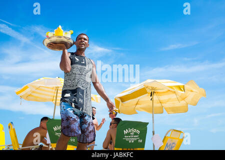 RIO DE JANEIRO - 16. Februar 2017: Strand verkaeufers Ausverkauf Caipirinhas Anrufe an potenzielle Kunden am Strand von Ipanema. Stockfoto