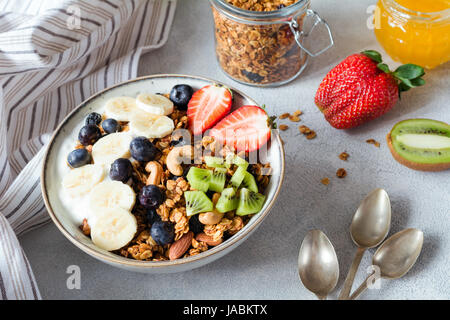 Müsli, Banane, Erdbeere, Kiwi, Heidelbeeren und Joghurt in eine Schüssel geben. Gesundes Frühstück-Hafer-Müsli Stockfoto