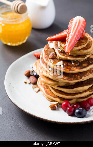 Stapel von Pfannkuchen mit frischen Beeren und Honigsirup auf weißen Teller-Detailansicht Stockfoto