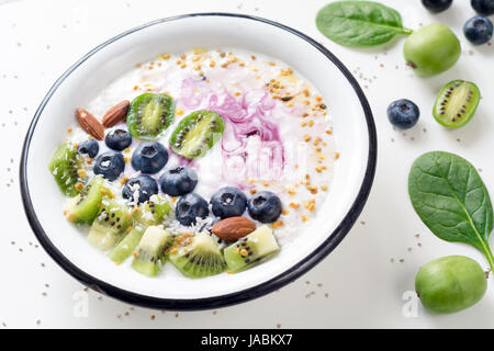 Smoothie-Schüssel mit Acai-Beere, Kiwi, Heidelbeeren, Mandel, Kokos, Bee Pollen und Baby Spinat auf weißem Hintergrund. Gesunde Entgiftung Smoothy Schüssel für Gesundheit Stockfoto