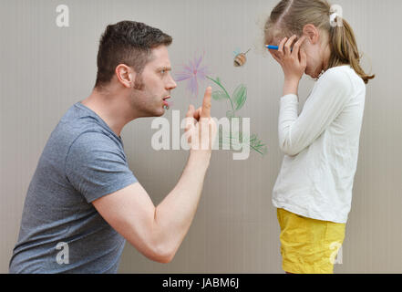 Kleines Mädchen verwöhnt die Tapete und ihr Vater ist wütend. Stockfoto