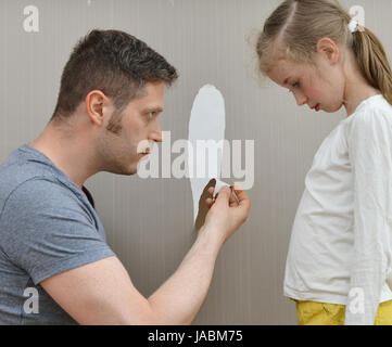 Kleines Mädchen verwöhnt die Tapete und ihr Vater ist wütend. Stockfoto