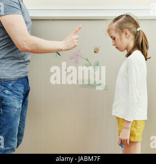 Kleines Mädchen verwöhnt die Tapete und ihr Vater ist wütend. Stockfoto