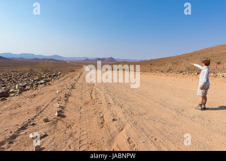 Touristen zu Fuß auf 4 x 4-Straße durch die bunte Wüste bei Twyfelfontein, in der majestätischen Damaraland Brandberg, malerischen Reiseziel in Namibia, Stockfoto