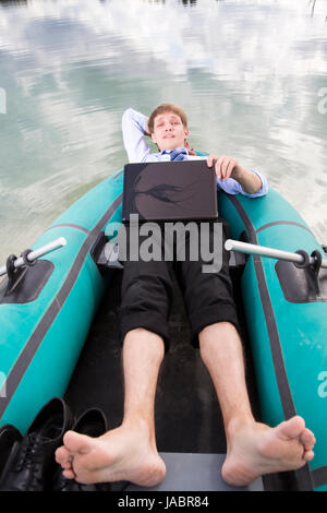 Gekleidete Mann lag im Boot und nehmen Sie sich Zeit Stockfoto