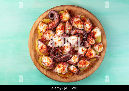 Eine obenliegende Foto von Pulpo a la Gallega, eine Krake mit gekochten Kartoffeln, typische spanische galizische Gericht, auf einer traditionellen hölzernen Platte eine Krickente backg Stockfoto