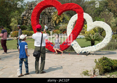 Ein Vater nimmt ein Foto seiner Tochter in einem Park in Mandalay, Myanmar (Burma) Stockfoto