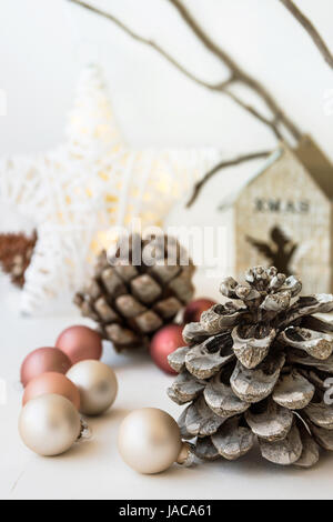 White Christmas-Dekoration-Zusammensetzung, großer Tannenzapfen, verstreuten Kugeln, glänzenden Stern, hölzerne Kerzenständer, trockene Äste im Hintergrund, skandina Stockfoto