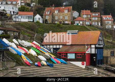 Abends Blick auf ziemlich malerischen Dorf an der Küste, Häuser am Meer, alte Rettungsboot Haus & bunte Boote auf Helling - Runswick Bay, Yorkshire, England, UK. Stockfoto