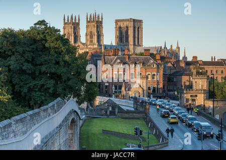 Landschaftlich reizvolle Stadtlandschaft von York - Blick auf die historischen Mauern (sonnenbeleuchtete Minster-Türme, Lendal Bridge, abendlicher Verkehr auf der Straße) - North Yorkshire, England, Großbritannien. Stockfoto