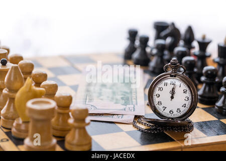 Vintage Tasche Uhr Geld und Schach Stücke auf Schachbrett Stockfoto