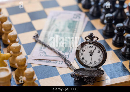 Vintage Tasche Uhr Geld und Schach Stücke auf Schachbrett Stockfoto