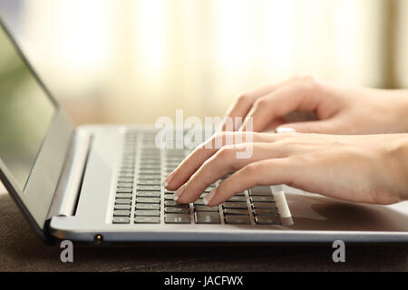 Nahaufnahme einer Frau Hände Tippen auf einer Laptoptastatur mit einem Fenster und ein warmes Licht im Hintergrund Stockfoto