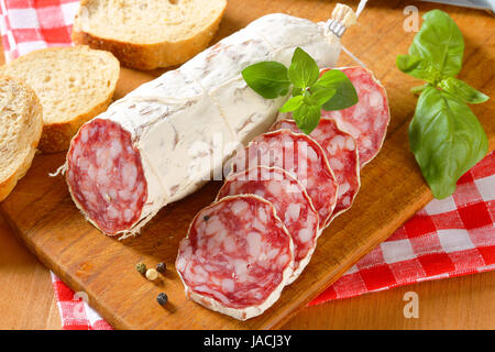 Französische Saucisson Sec und geschnittene knusprige Rolle auf Schneidebrett Stockfoto