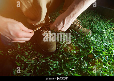 Mann, die Schnürsenkel zu binden, auf seine aktiven Schuhe Closeup grün Hintergrund Stockfoto