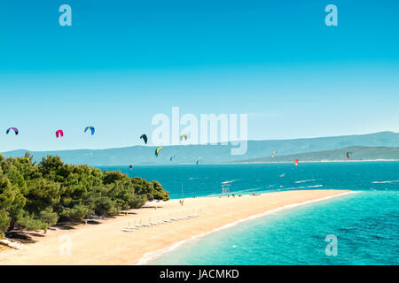 Blick auf das Wahrzeichen Goldene Horn auf der Insel Brac in Kroatien. Kitesurfer und Windsurfer im Hintergrund beleben die malerische Szenerie. Stockfoto