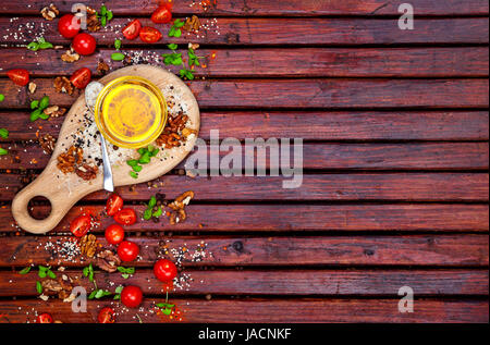 Essen-Hintergrund mit Textfreiraum. Gewürze, Cherry-Tomaten, Basilikum und Pflanzenöl auf dunklen Holztisch, Ansicht von oben Stockfoto