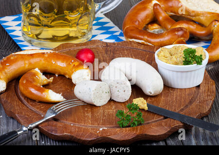 Rundes Holzbrett Mit Weißwurst, Brezel, Senf Und Radieschen Und Einem Glas Mit Bier Auf Einem alten Rustikalem Holztisch Stockfoto