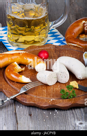 Rundes Holzbrett Mit Weißwurst, Brezel, Senf Und Radieschen Und Einem Glas Mit Bier Auf Einem alten Rustikalem Holztisch Stockfoto