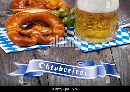 Ein Glas Mit Bier, Brezeln Und Once Hopfendolden Auf Einem alten Rustikalen Holztisch Mit Einem Blauen Banner Mit der Aufschrift Oktoberfest Stockfoto