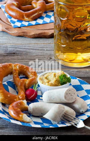 Blau-Weißer Pappteller Miit Weißwurst, Brezel, Senf Und Radieschen Und Einem Glas Mit Bier Auf Einem alten Rustikalem Holztisch Stockfoto