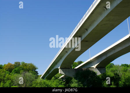 Paar große konkrete Autobahnbrücken gegen klar blauer Himmel und Wald. Stockfoto