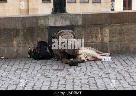 Ein Bettler bettelt und sein Hund lag auf der Straße, auf der Zufahrt zur Karlsbrücke, Prag, Tschechien Stockfoto