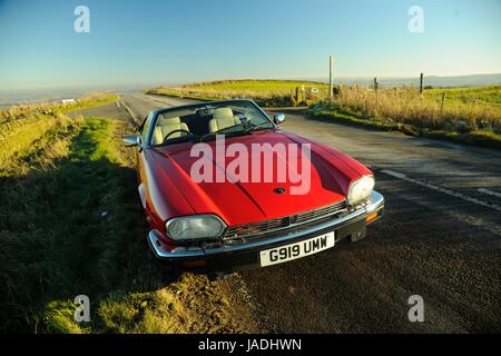 Ein rotes Jaguar XJS Cabriolet parkte an einem sonnigen Wintertag auf einer Landstraße Stockfoto